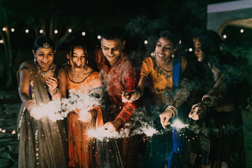 pexels-photo-7686379-7686379 A group of friends enjoying Diwali night with sparklers in traditional clothing.